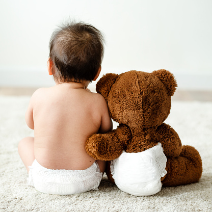 Back of a baby with a teddy bear